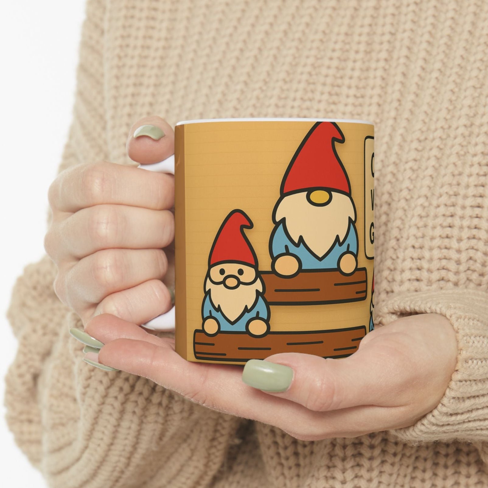 Person holding a mug with gnome design, wearing sweater.