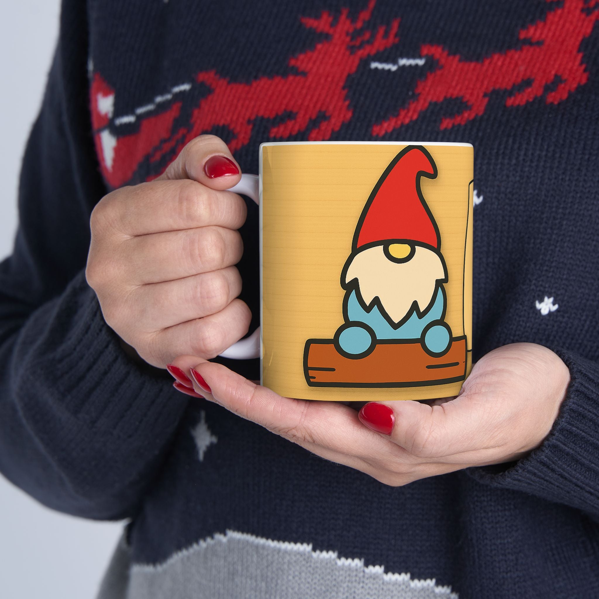Person holding a mug with a gnome design, wearing a dark sweater.
