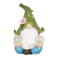 Cross-legged gnome with a green leaf-shaped hat, pink flower, white beard and a clear globe in each hand.