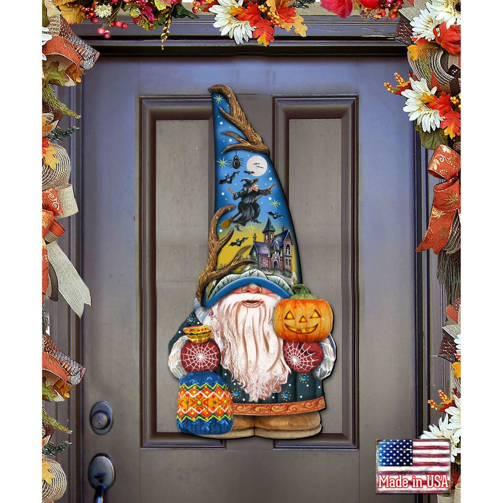 Halloween door decoration with a blue-hatted gnome holding a jack-o'-lantern; its hat depicts a witch, moon and haunted house.