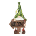 Gnome with a green leaf hat and flower holding a wooden-style Welcome arrow sign with a ladybug.