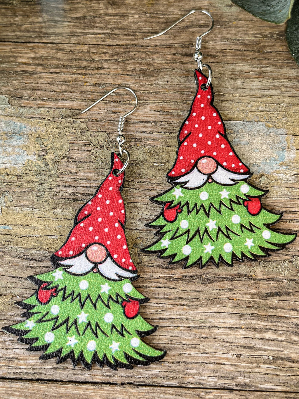 Pair of drop earrings shaped like Christmas tree gnomes with red spotted hats, white mustaches and green branches.