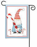 Christmas garden flag showing a blue-coated gnome in a red-and-white striped hat holding a large candy cane.