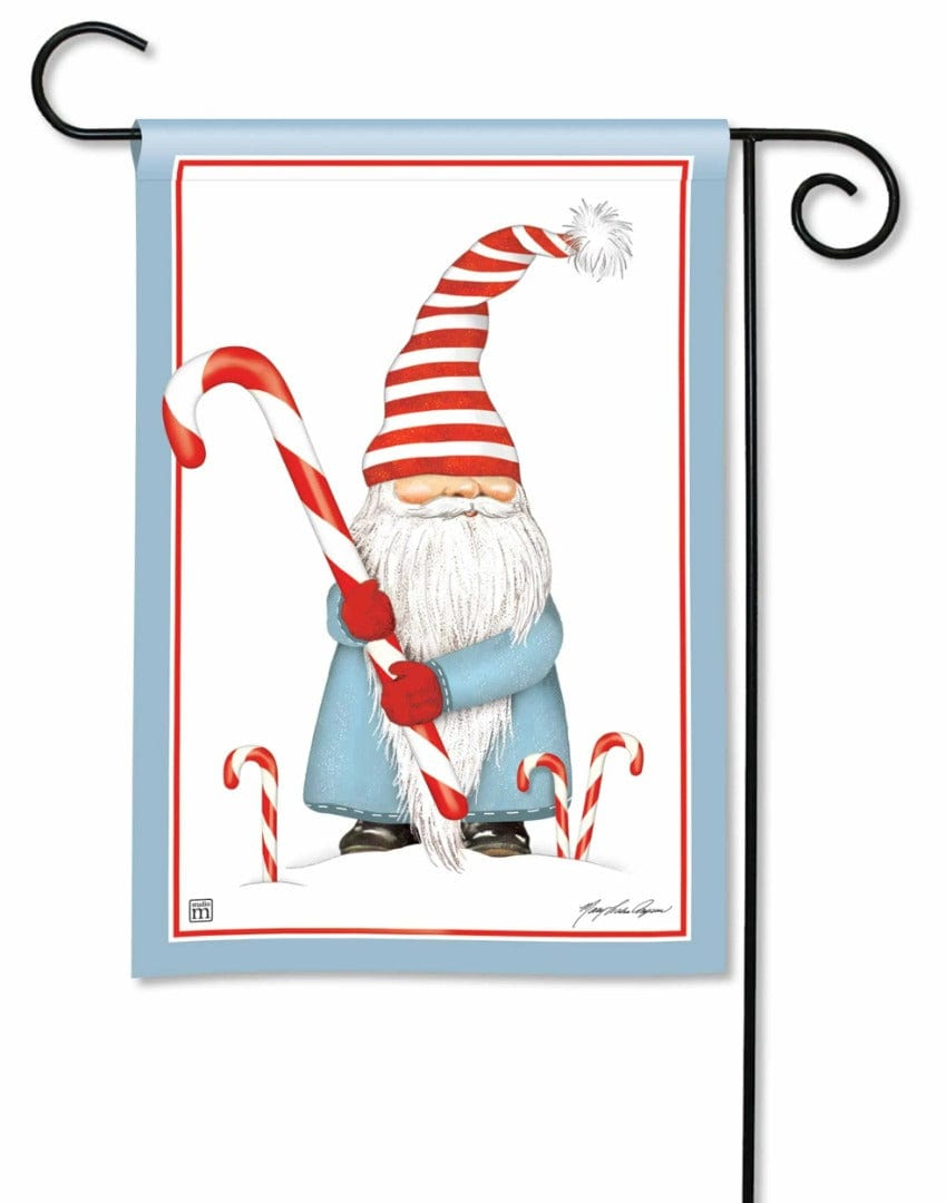 Christmas garden flag showing a blue-coated gnome in a red-and-white striped hat holding a large candy cane.