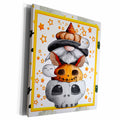 Canvas wall art with a yellow border showing a gnome stacked above a jack-o'-lantern and gray skull among stars.