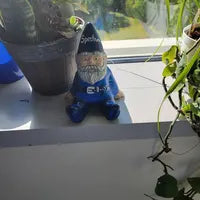 Garden Gnome  customizable figurine with a blue hat on a windowsill with plants