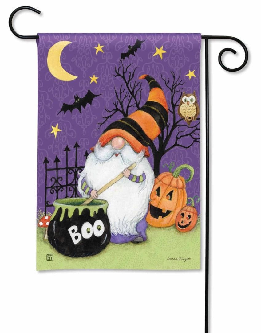 Purple garden flag showing a striped witch-hatted gnome stirring a BOO cauldron beside pumpkins, bats and an owl.