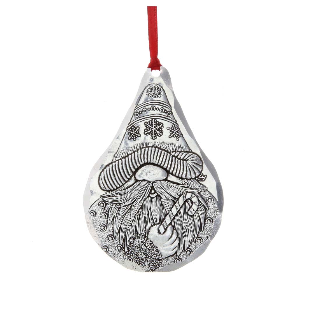 Silver-colored teardrop ornament engraved with a bearded gnome holding a candy cane, hung from a red ribbon.