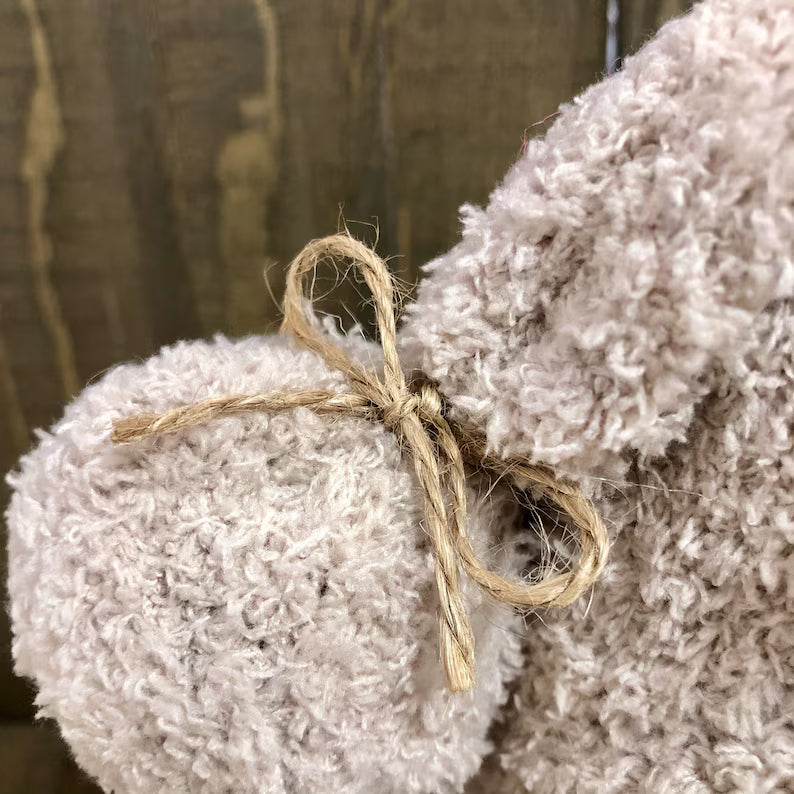 Textured beige fabric with twine bow against a wooden background