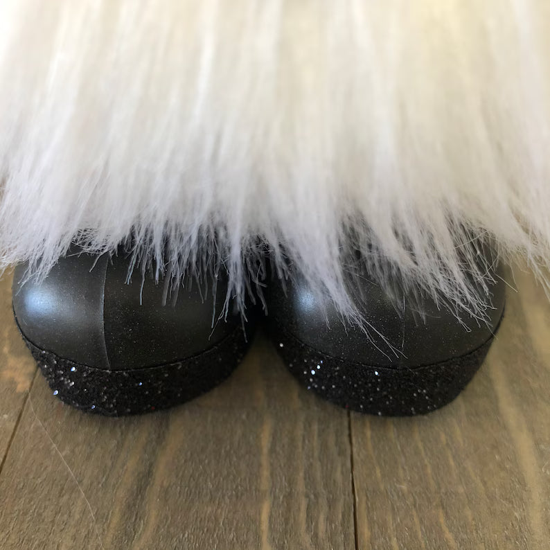 Black shoes with white fur trim on a wooden floor