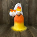 Decorative gnome with candy corn hat and beard on a wooden background