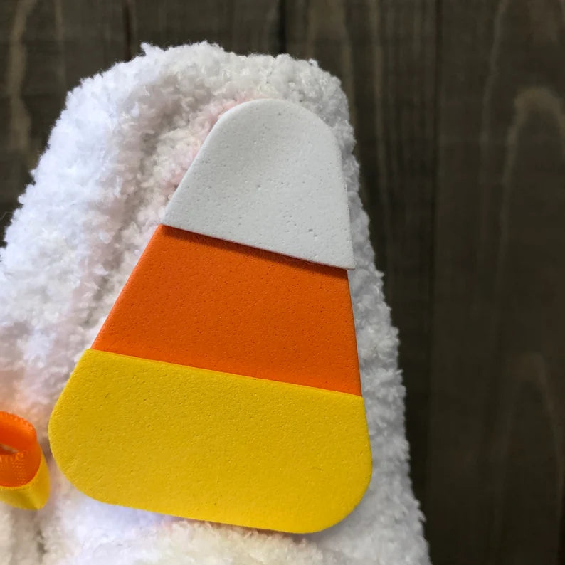 Candy corn-shaped toy attached to a plush toy with a blurred background
