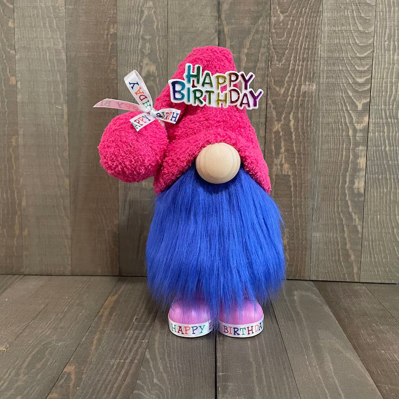 Gnome with pink hat and blue beard on a wooden floor, with 'Happy Birthday' text.