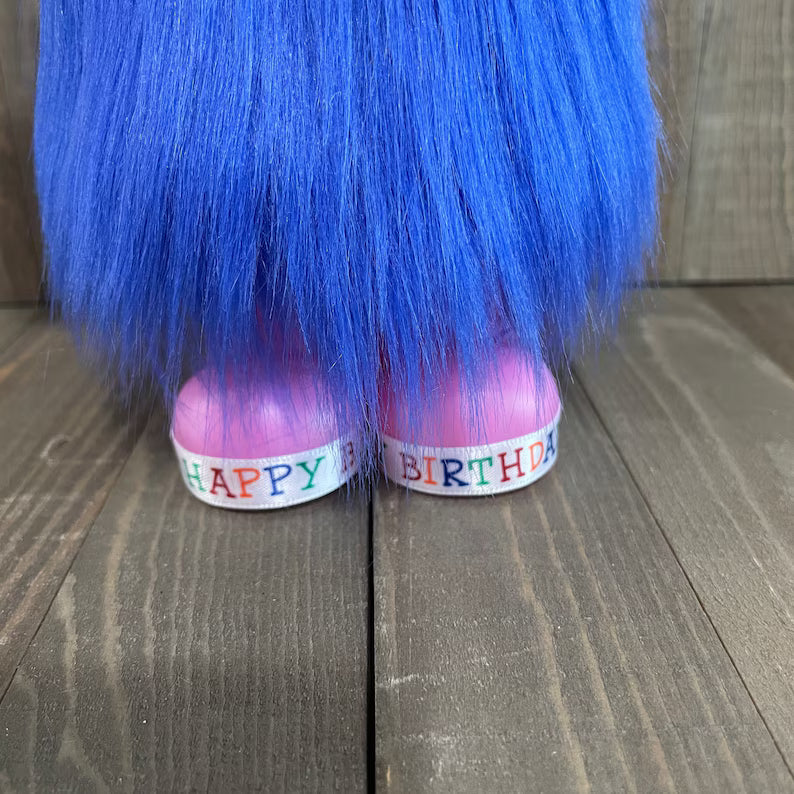 Blue hair extensions with 'Happy Birthday' bands on a wooden surface