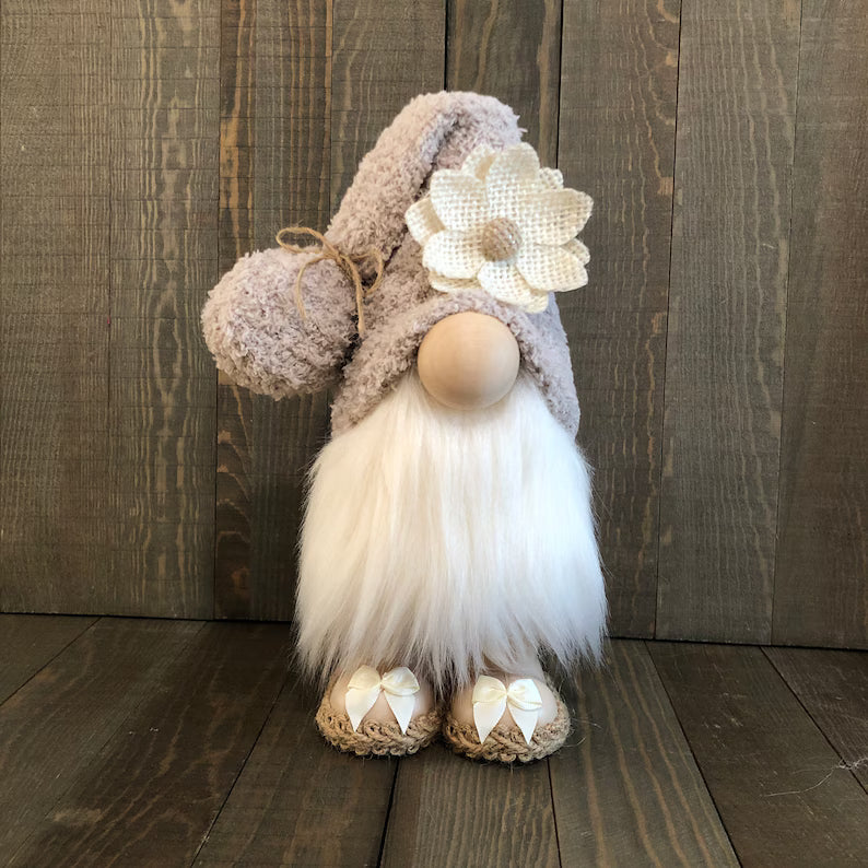 Decorative gnome with a flower hat on a wooden floor against a wooden wall.