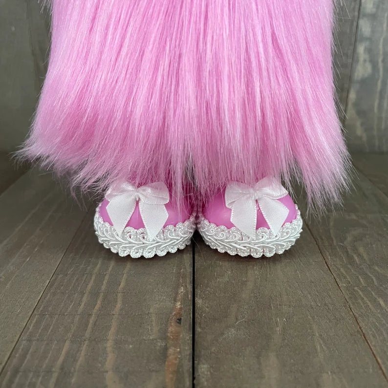 Pink furry legs with white shoes and bows on a wooden floor