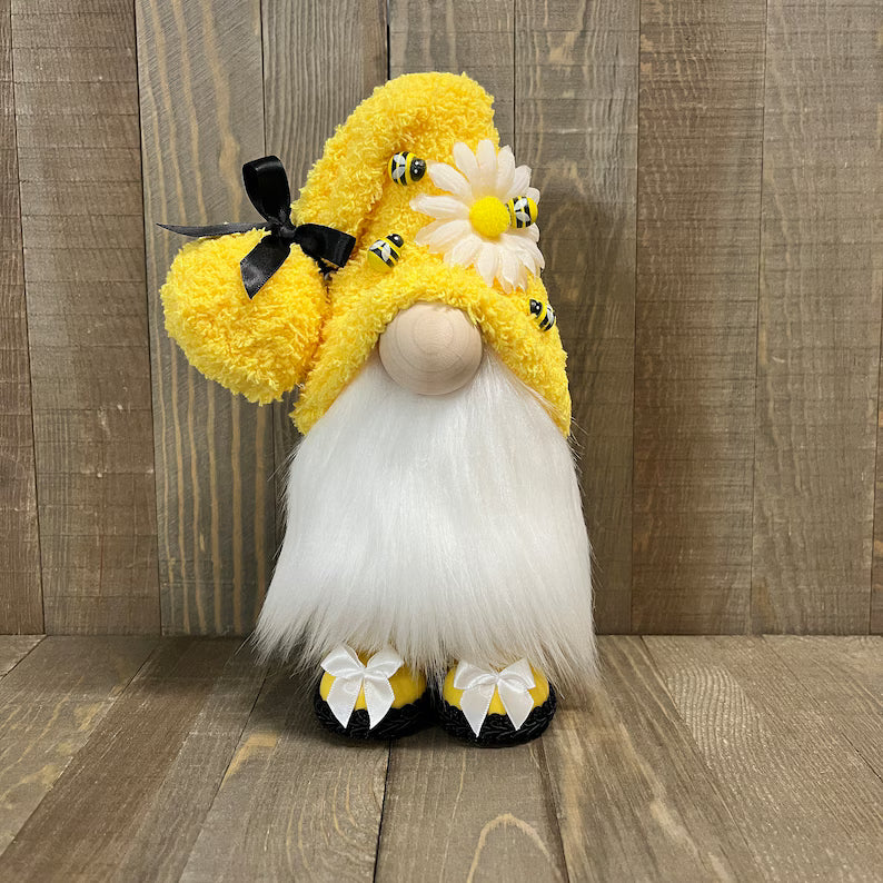 Gnome with yellow hat, white beard, and black shoes on a wooden floor.