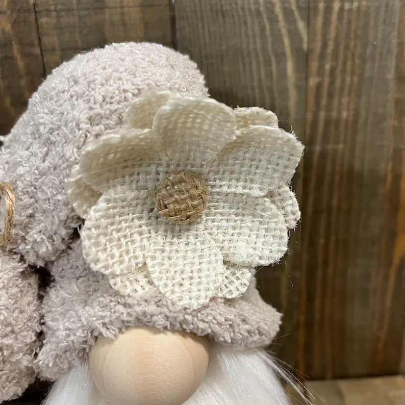 Decorative gnome with a flower on a wooden background