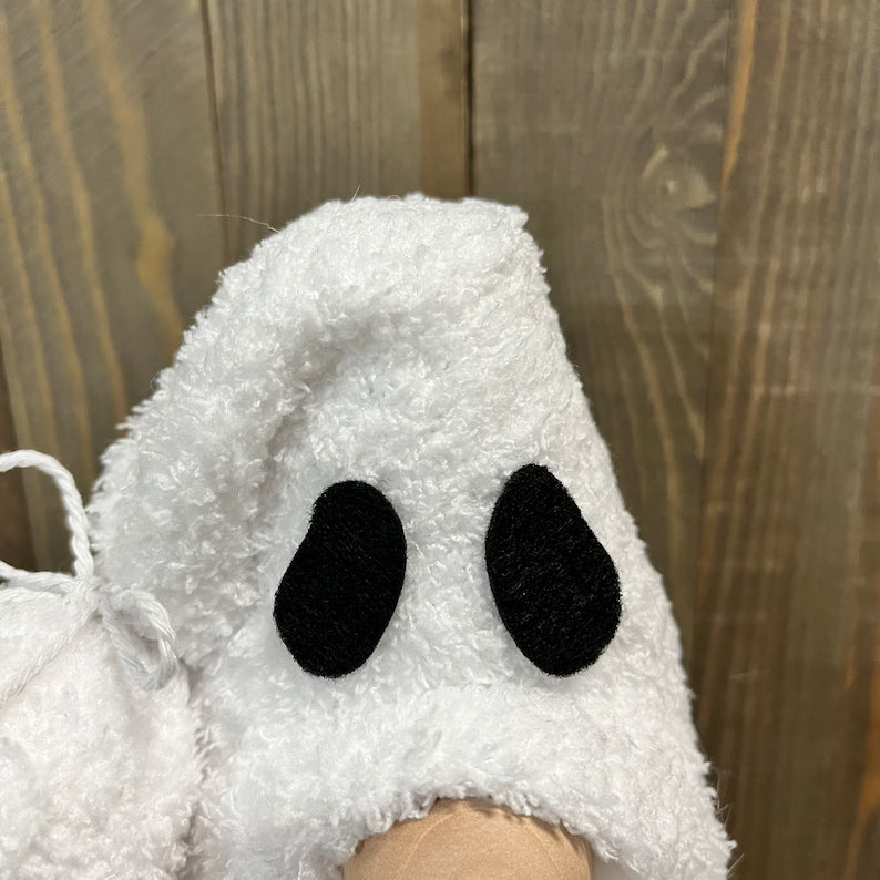 White ghost-shaped plush toy against a wooden background