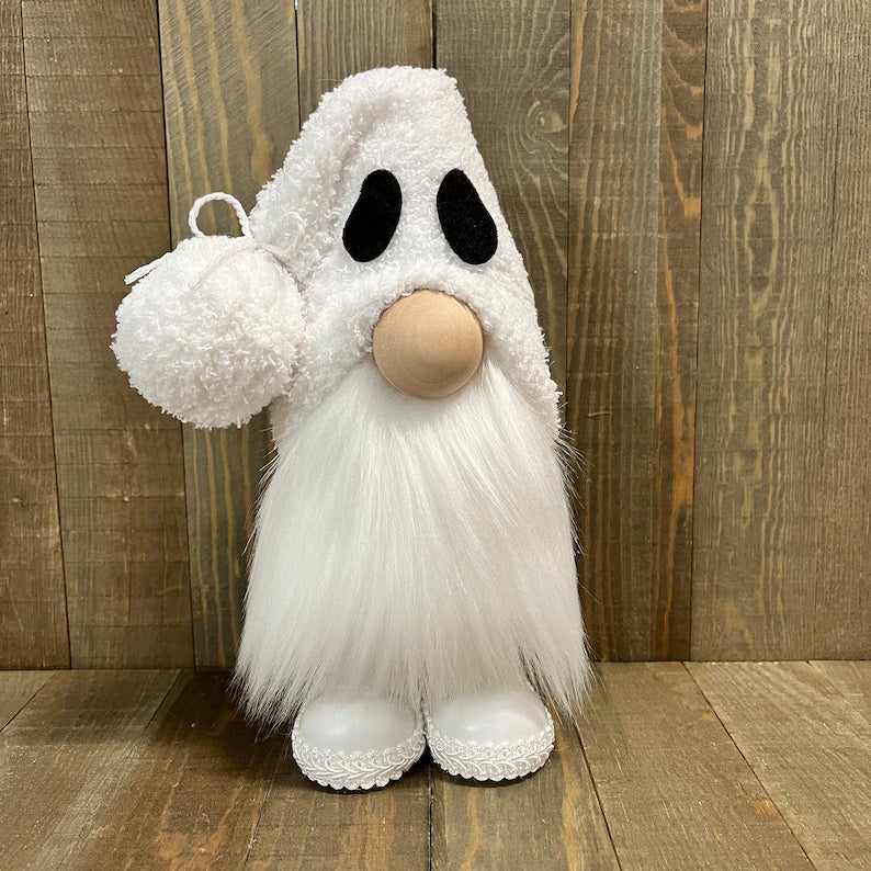 White plush ghost toy with black eyes and a round nose on a wooden floor.