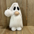 White plush ghost toy with black eyes and a round nose on a wooden floor.