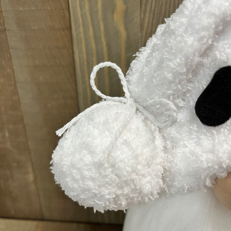 Close-up of a white plush toy with a black nose against a wooden background