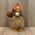 Handcrafted Thanksgiving gnome figurine with a turkey hat on a wooden background