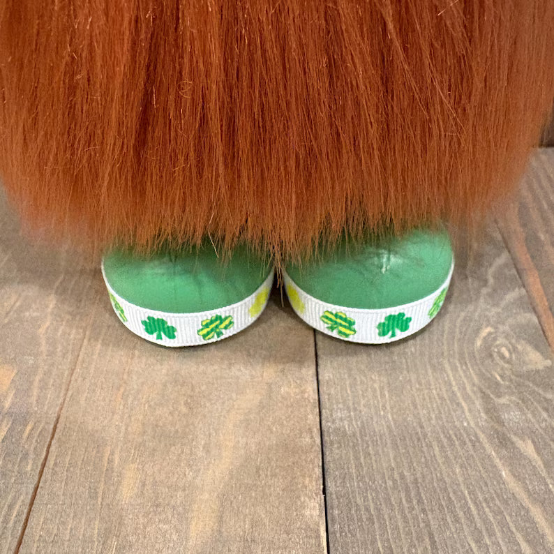 St. Patrick day handcrafted gnome with green shoes with shamrock design on a wooden floor