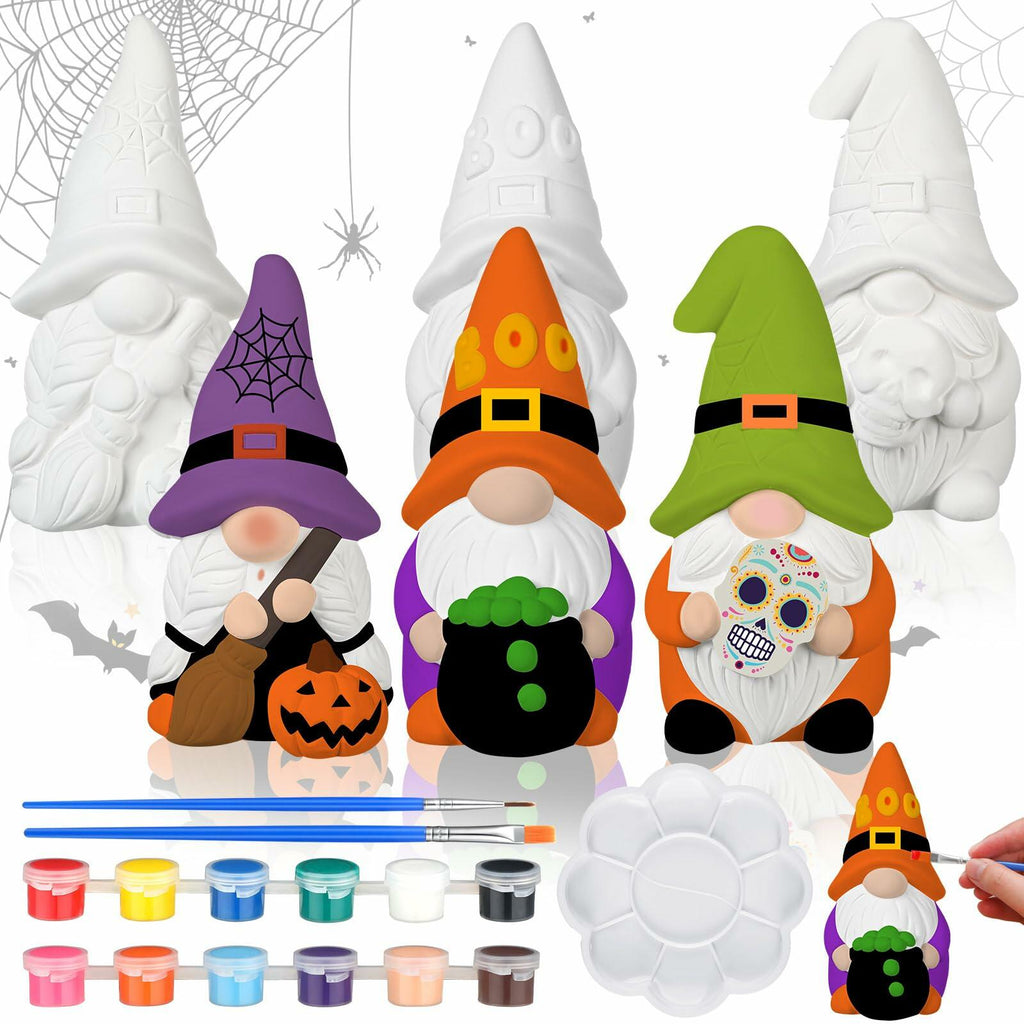 Three white unpainted Halloween gnomes behind painted examples, with paint pots, brushes and a palette in the foreground.
